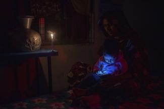 Entwicklungserfolge erfordern Eigenverantwortung: Eine Dreijährige spielt während eines Sturms mit dem Handy ihrer Mutter in einem Zyklonbunker. Bangladesch im Jahr 2022. 
