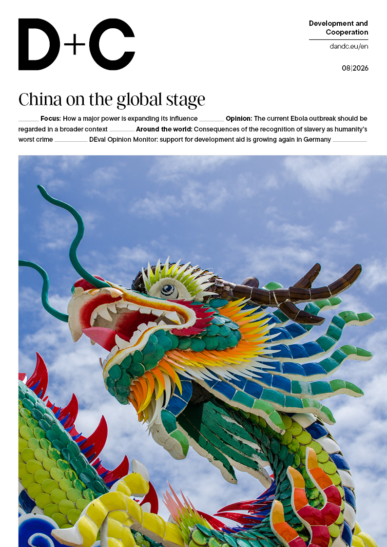Colourful Chinese dragon statue with open mouth and green scales against a blue, cloudy sky.