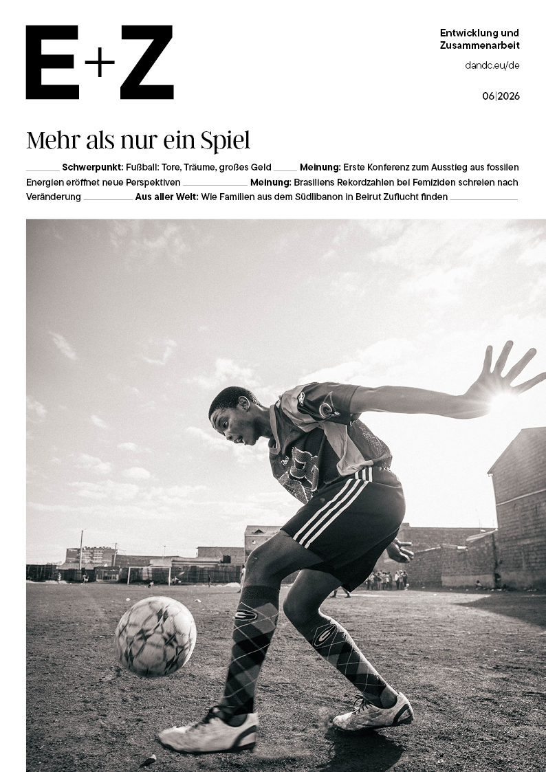 Schwarz-weißes Titelbild der Zeitschrift „E+Z“ (06/2026) mit der Überschrift „Mehr als nur ein Spiel“, auf dem ein Fußballer auf einem staubigen Spielfeld einen Ball jongliert.