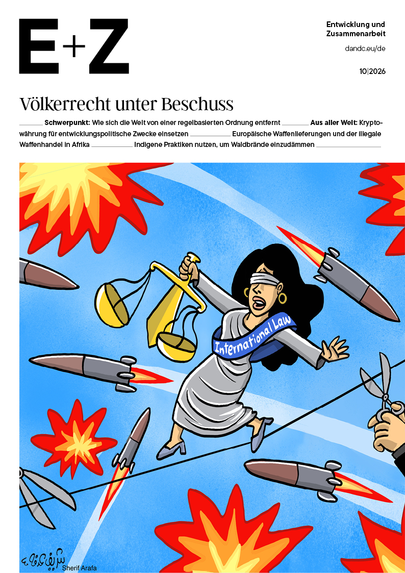 Karikatur: verbundene Justitia mit Waage und „International Law“-Schärpe, umgeben von Raketen und Explosionen, rechts schneidet eine Hand ein Seil.
