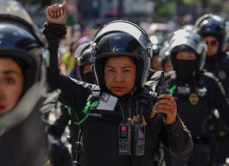 The Green Wave has spread across Latin America: A policewoman raises her arm as she guards members of feminist collectives protesting in the streets of Mexico City in 2023. She wears a green ribbon in solidarity. 