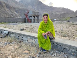 Parveen Bibi in Darkut Colony in front of a water tank that is filled by a solar-powered pump.