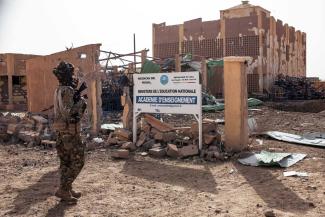 A fighter of the Azawad Liberation Front (FLA) stands in front of the Regional Academy of Education building in Kidal, northern Mali, in May. The building was severely damaged during fighting prior to the FLA’s capture of the city.