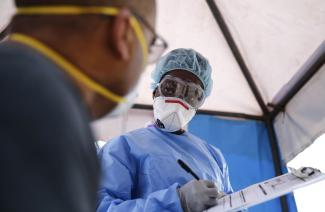 Testing capacities are improving fast: Kenyan lab assistant attending to a patient before a test.