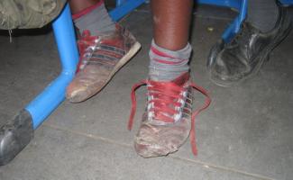 Attending school helps children from poor families escape poverty: footwear seen in a Nairobi classroom.