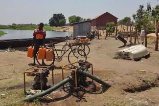 Water carrier in Terakeka, South Sudan, with jericans of Nile water on sale.