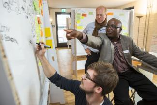 Jonas Rehmet von Better Today (vorne), Felix Nkulukusa, ehemaliger Staatssekretär im sambischen Finanzministerium (Mitte), und Jörn-Hendrik Müller-Bornemann  von der GIZ im  „lab of tomorrow“.