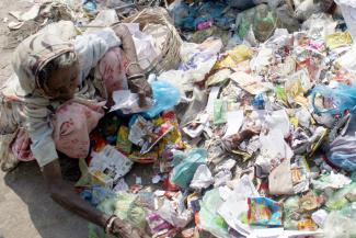 Destitute woman sorting plastic waste on a Karachi street.