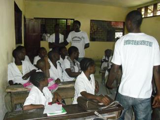 "Se protéger c'est bien, mais l'abstenir c'est mieux" (it is good to protect oneself, but abstention is better)DUCA campaigners in the class room): DUCA staff campaigning for "Sensibilisation pour la sexualité responsable" (Awareness for responsible sexuality) in a class room. (Pardey)