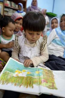 Kleinkind mit Bilderbuch in Aceh.